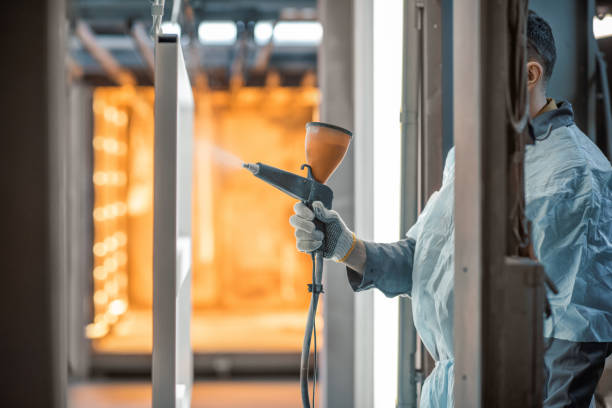 Painter in protective wear paints metal products with powder paint. Powder coating process at the manufacturing. High quality photo